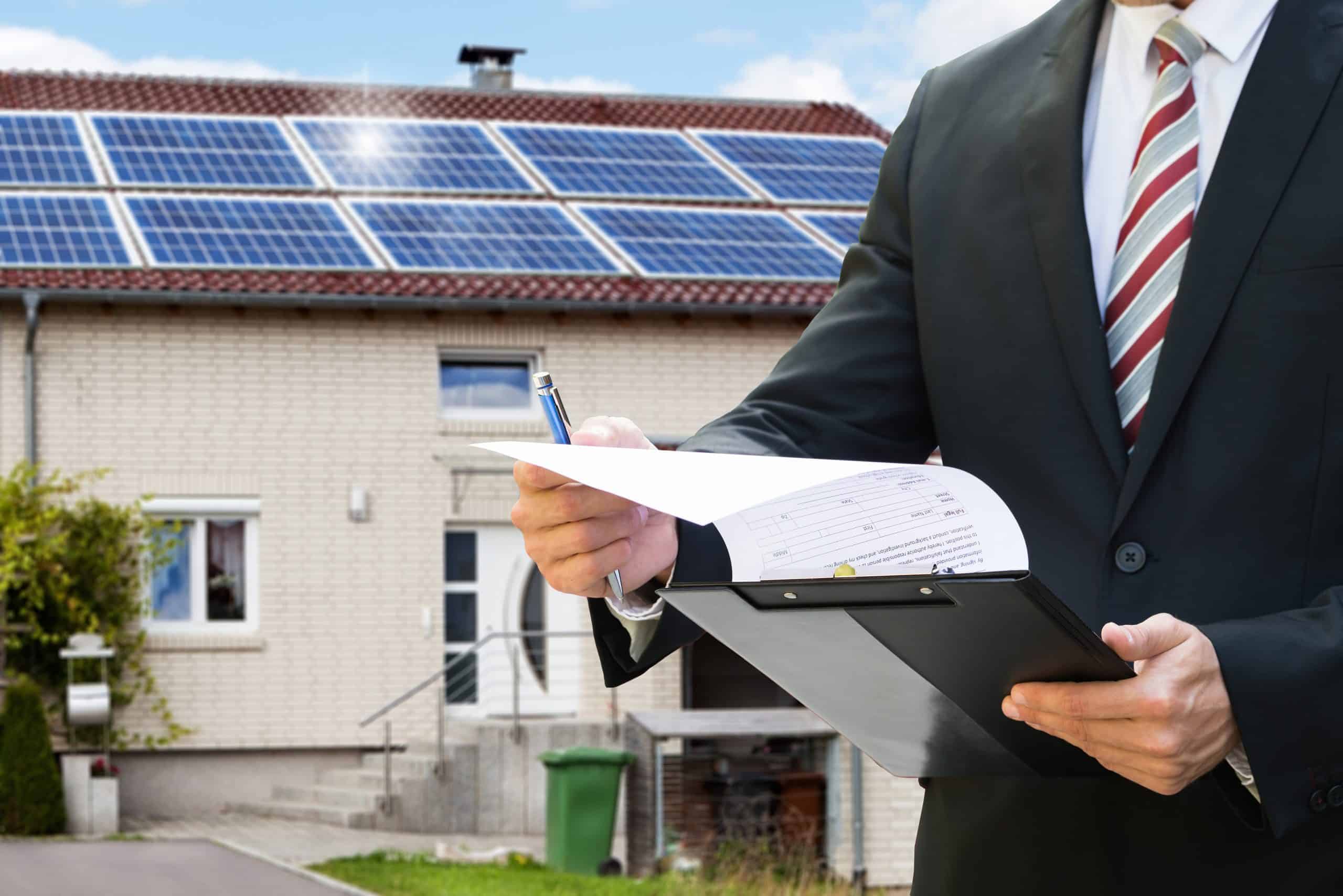 Midsection Of A Man Checking Documents Standing Near House With Solar Panels On Roof